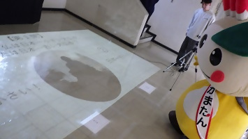 床に映し出されるクイズを見るかまたんの写真