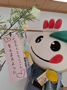 笹に短冊をつるそうとするかまたんの写真