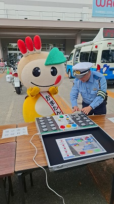 反射神経診断測定の機械の使い方を警察の方が説明している写真