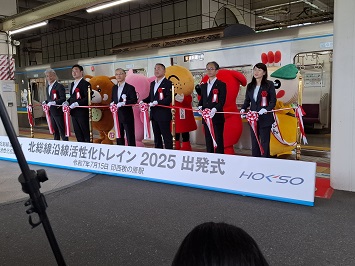 テープカットをする来賓の皆様とキャラクター達の写真