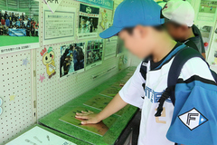 選手の手形と合わせる子供の写真